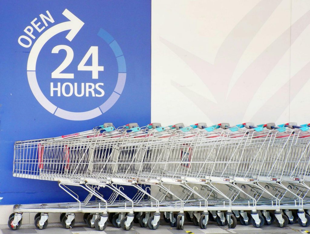 Row of shopping trolleys outside a 24-hour supermarket in Singapore, emphasizing convenience and accessibility.